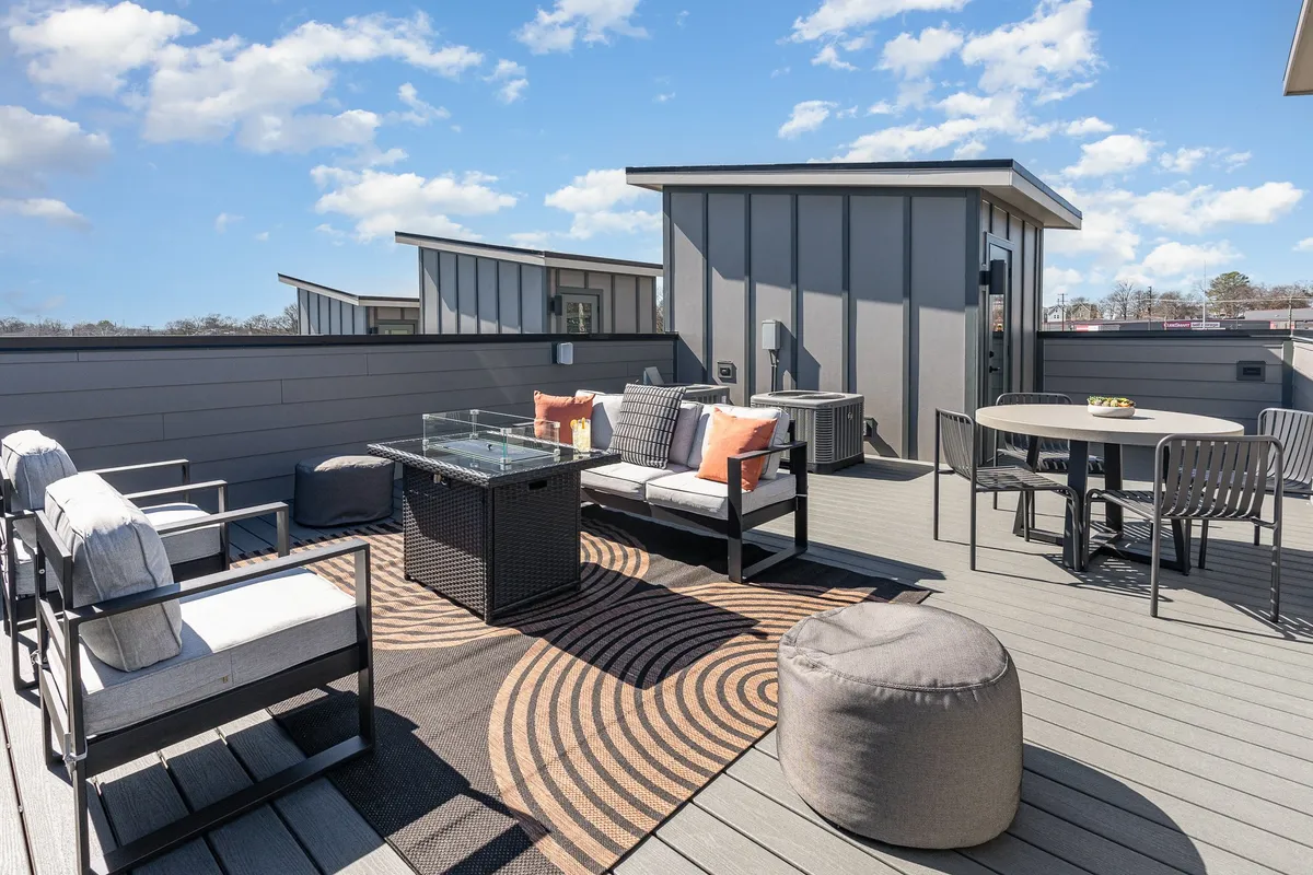 The hero image showcases a stylish rooftop patio at sunset, featuring a cozy outdoor seating area with plush decorative pillows, a glass coffee table, and a dining table ideal for group gatherings. The contemporary design and soft evening light create an inviting atmosphere perfect for relaxing or entertaining under the stars.