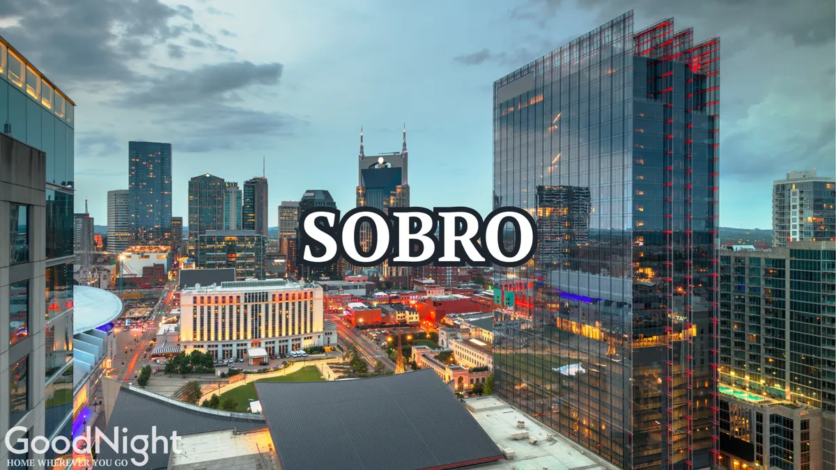 A panoramic view of the Nashville city skyline at night, with tall buildings, neon lights, and the river in the foreground. The scene exudes energy and is perfect for envisioning evenings on a rooftop patio with friends and the city as a backdrop.