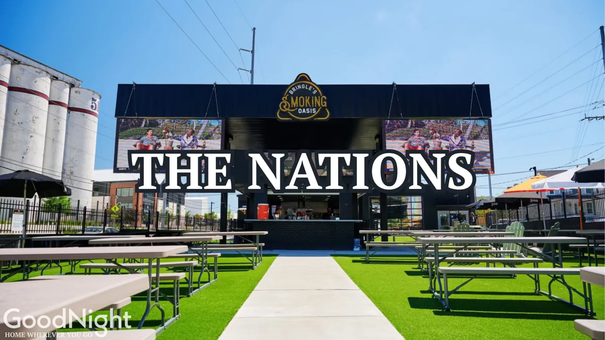 A vibrant exterior scene featuring a large 'THE NATIONS' signage, an inviting outdoor seating area, and a dedicated space for al fresco dining and social gatherings. The area is well-lit and designed for group events, with ample room for people to connect and relax together outdoors.