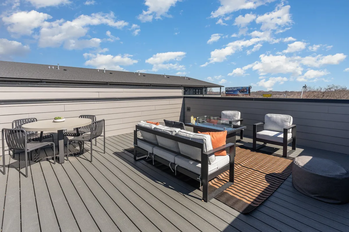 This image showcases an inviting outdoor patio furnished with a dining table set amidst comfortable seating. The view captures the sky above, suggesting a pleasant open-air environment ideal for gatherings. The overall atmosphere is casual and welcoming, with enough space for both lively group meals and quieter moments.