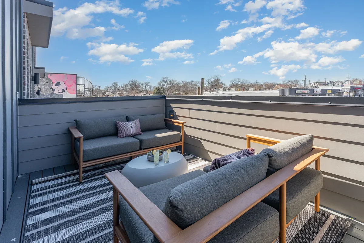 This image presents a comfortable outdoor seating arrangement adorned with decorative pillows, centered around a round coffee table. The design invites guests to relax and socialize while enjoying the open air, perhaps watching the sunset or stargazing.